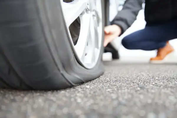 Ein Auto mit platten Reifen steht auf Asphalt. Die Frage ist, wie lange kann ein Auto auf einem platten Reifen stehen, bevor es beschädigt wird?
