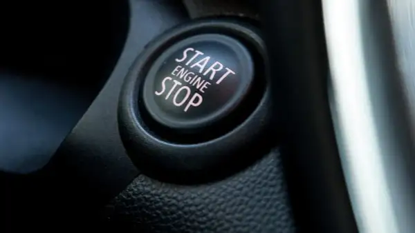 Nahaufnahme eines Start/Stop-Knopfes im Auto. Der Knopf ist schwarz mit rosa Schrift.