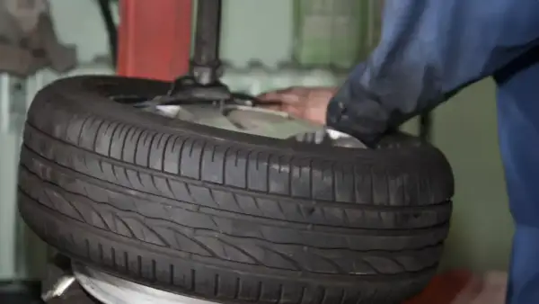 Ein Mechaniker wechselt einen Reifen. Die Frage "was kostet ein reifenwechsel" beschäftigt viele Autofahrer.