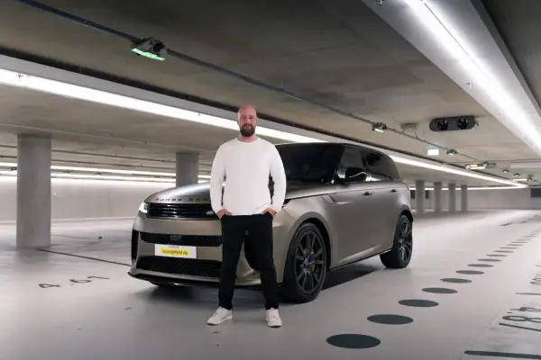 Mann steht neben einem Range Rover in einer Tiefgarage. Erste Range Rover Erfahrungen gesammelt.