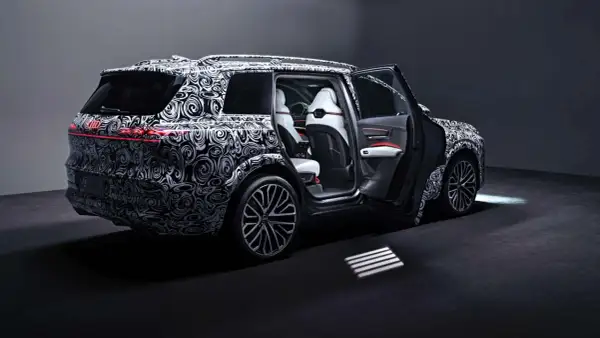 Der Audi SQ9, getarnt mit einem auffälligen Muster, zeigt seine luxuriösen weißen Ledersitze und die sportlichen Felgen.