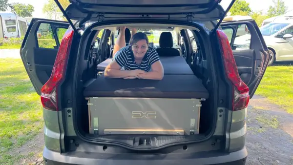 Frau liegt auf Bett im Dacia Jogger, bereit für den Camping-Test.