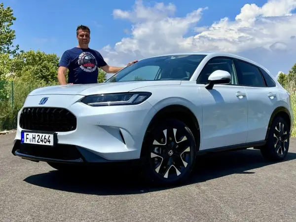 Mann steht neben einem weißen Honda ZR-V.