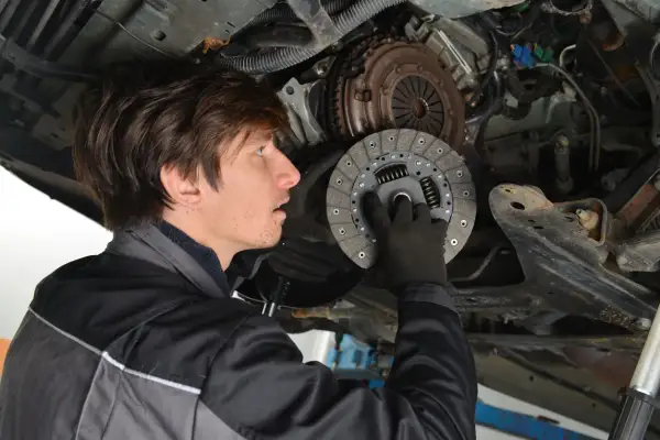 Mechaniker hält neue Kupplungsscheibe. Die Kosten für den Kupplung wechseln sind oft eine Überraschung.
