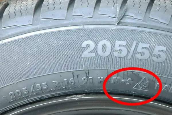Detailaufnahme eines Reifens mit der Kennzeichnung 205/55 R16. Das alpine Zeichen (Schneeflocke im Berg) bestätigt, dass dies ein Winterreifen ist.