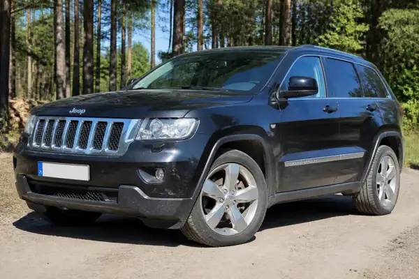Schwarzer Jeep Grand Cherokee 3.6 V6 im Wald. Hoffentlich keine Probleme mit diesem Geländewagen.