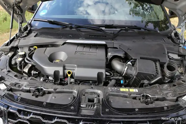 Motorraum eines Range Rover Evoque. Der Motor ist abgedeckt, aber die Leistung des Fahrzeugs, die durch die PS angegeben wird, ist spürbar.
