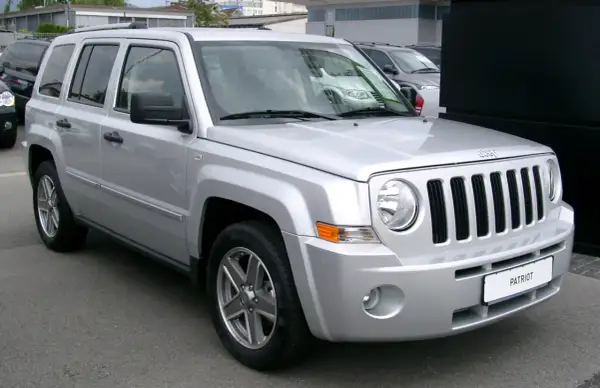 Silberner Jeep Patriot, der auf einem Parkplatz steht. Bekannt für seine Robustheit, aber auch für seine Jeep Patriot Schwachstellen, wie z.B. Rost an den Radläufen.