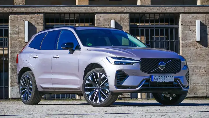 Ein silberner Volvo XC60 im Test, mit markantem Kühlergrill und LED-Scheinwerfern, steht vor einer Steinfassade.