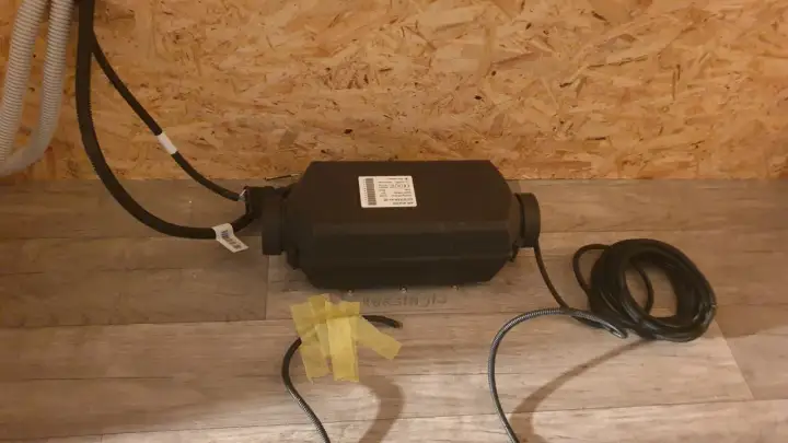 Einbau einer Standheizung: Das Gerät mit Kabeln liegt auf dem Boden, bereit für die Installation.